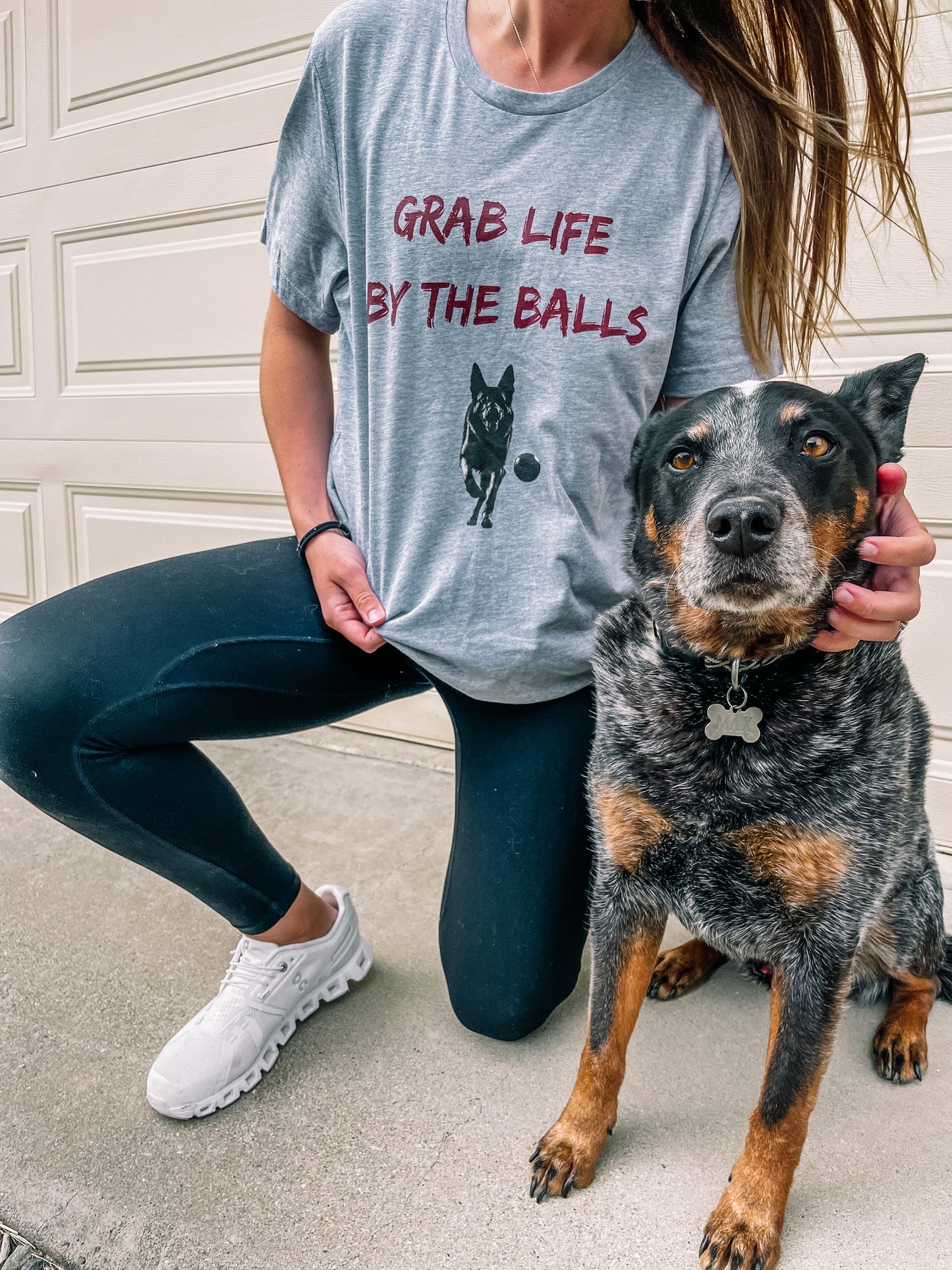 Dog owner and her dog wearing heather grey t-shirt with the slogan "Grab Life By the Balls" and an image of a dog chasing a ball