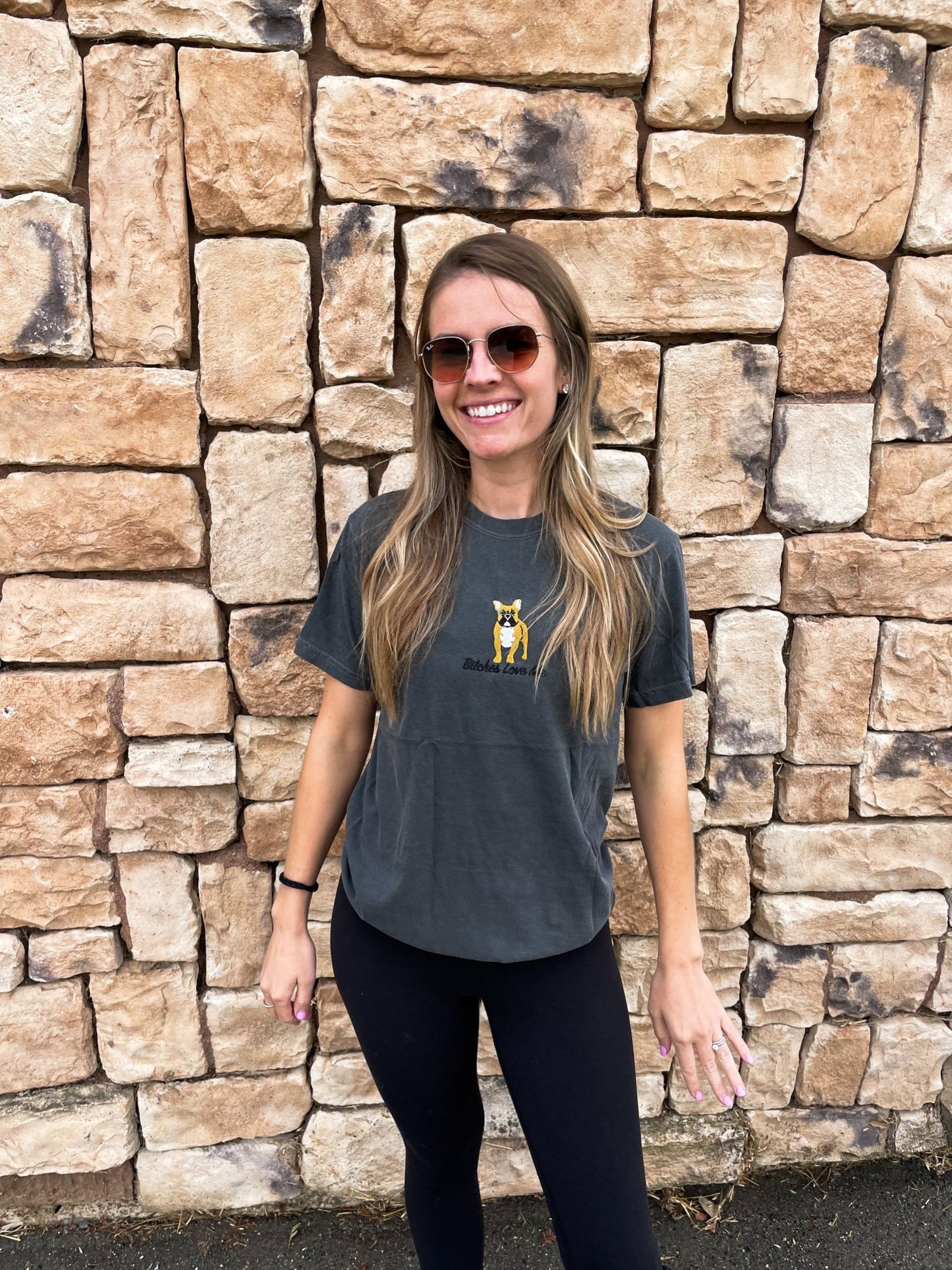 A woman wearing the Moe Sews x Grrub Pet "Bitches Love Me" Frenchie gray t-shirt while smiling.